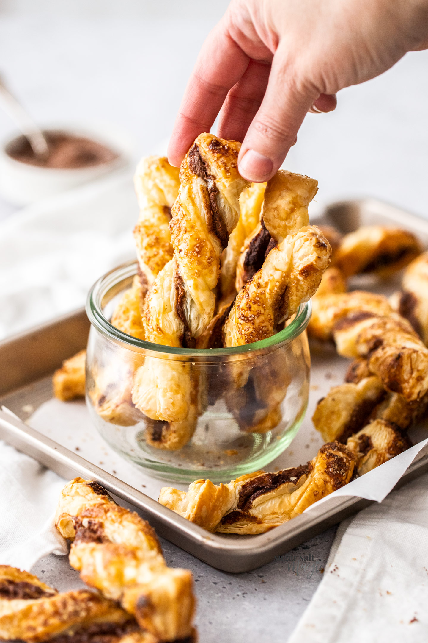 Nutella puff pastry twists standing up in a glass jar.