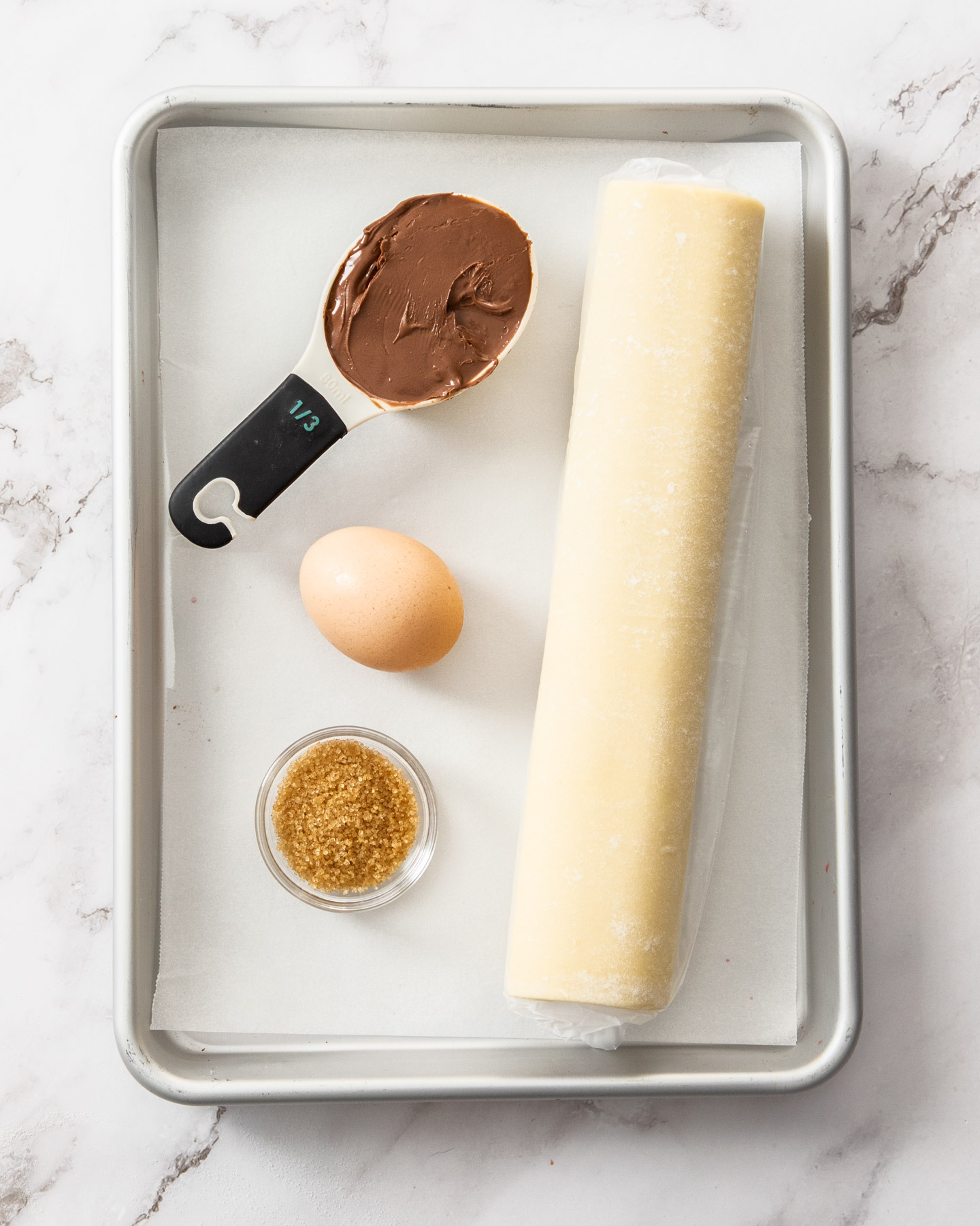 Ingredients for Nutella puff pastry twists on a baking tray.