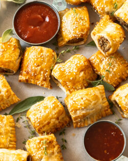 Close up of golden turkey sausage rolls on a baking tray with herbs.