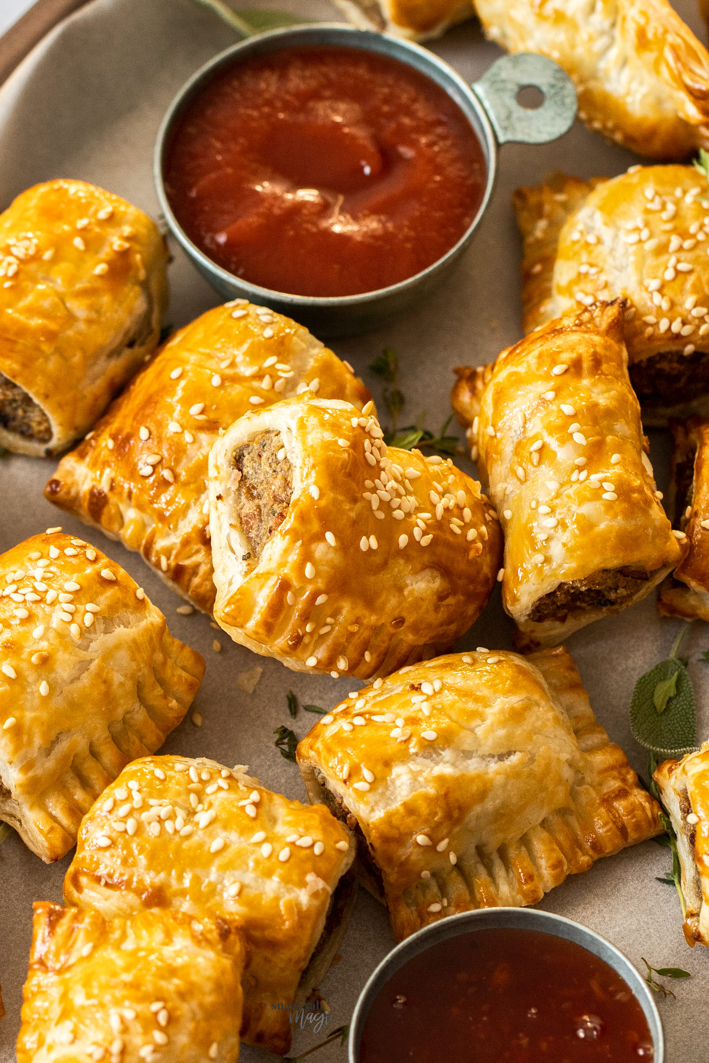 Top down view of sausage rolls with a pot of sauce.