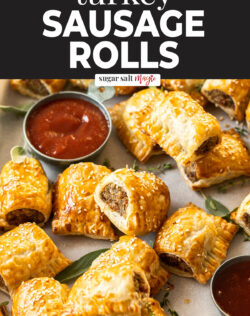 A batch of golden sausage rolls with a small pot of sauce.