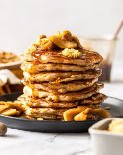 A stack of pancakes topped with apples and butter.