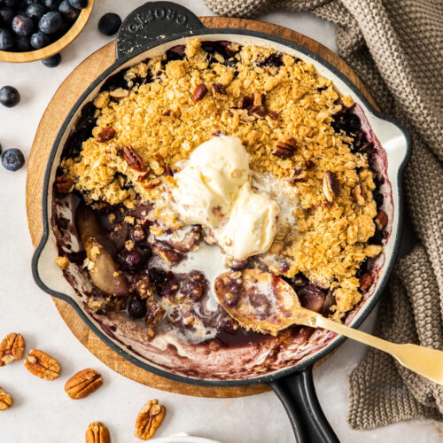 A skillet filled with pear and blueberry crumble.