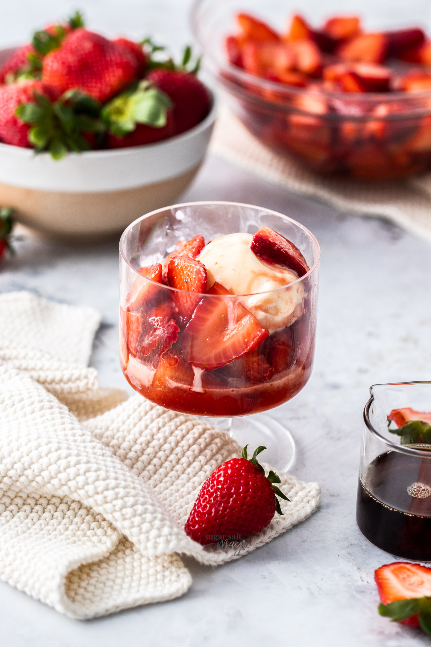 Macerated strawberries over some ice cream in a glass.