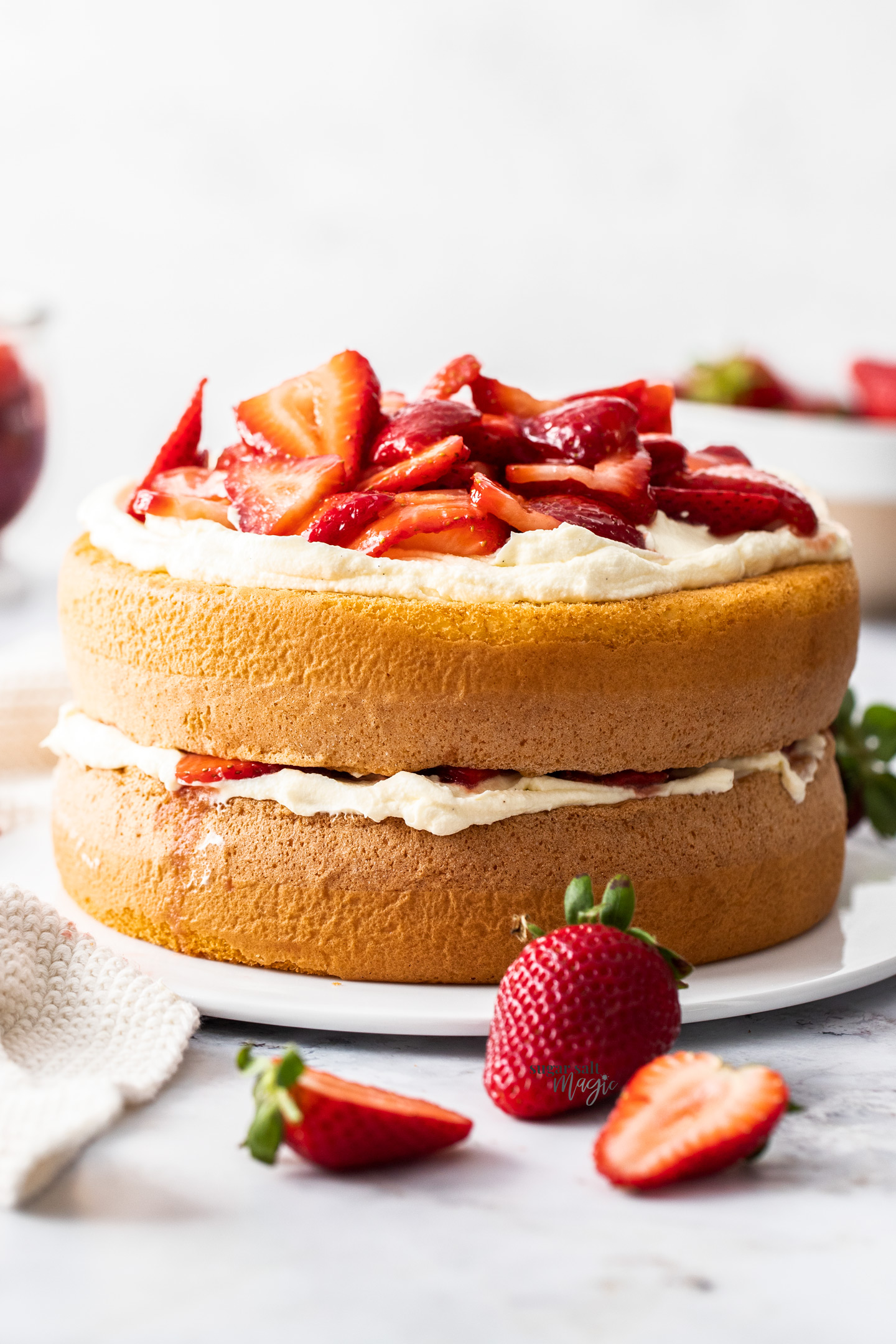 A two layer sponge cake topped with cream and strawberries.