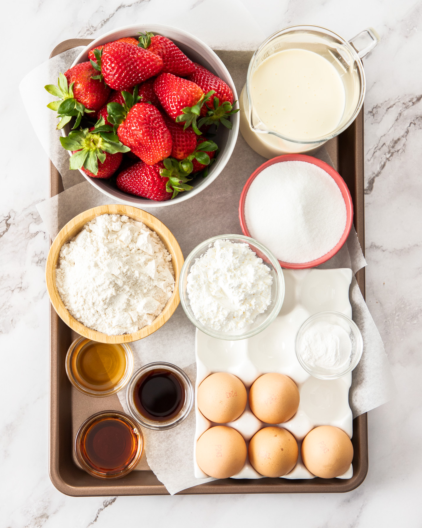 Ingredients for strawberry sponge cake on a baking tray.