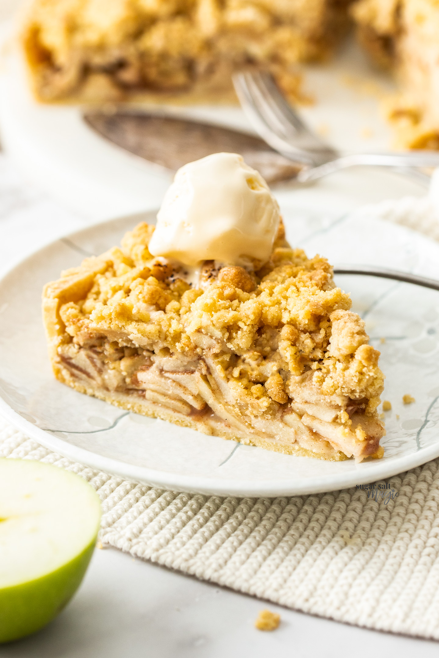 A slice of apple crumble tart topped with ice cream.