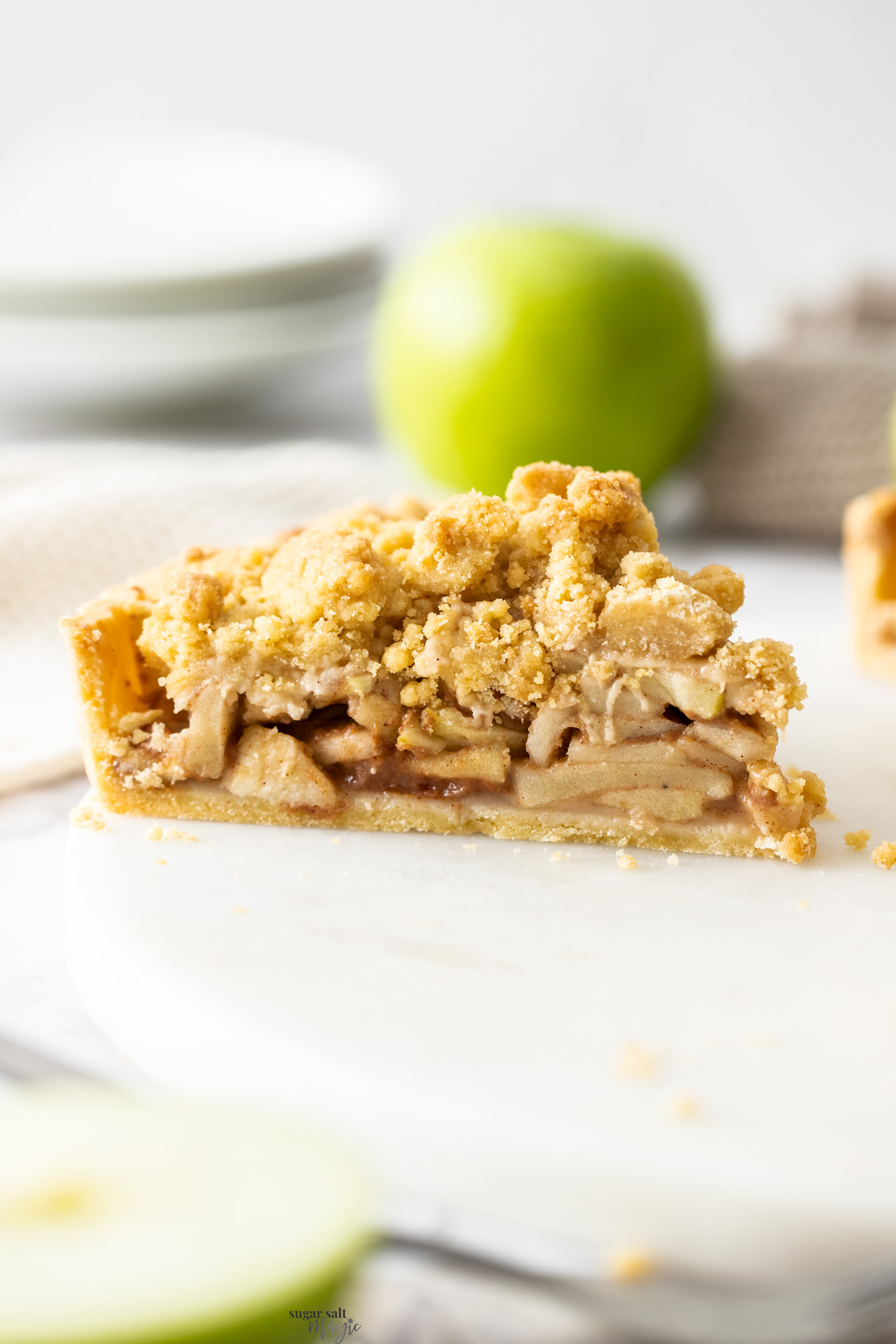 A slice of apple crumble tart on a marble platter.