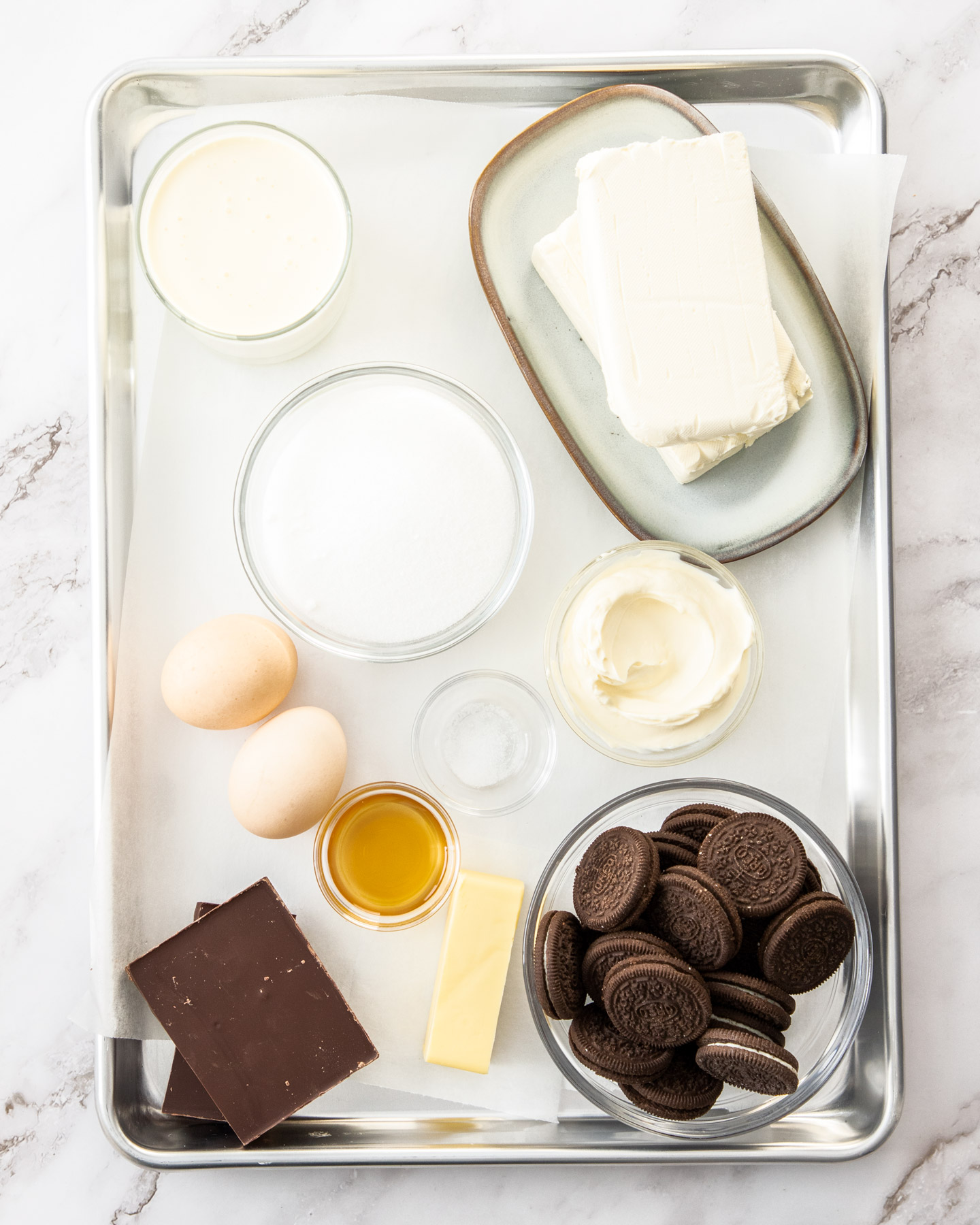 Ingredients for baked chocolate cheesecake on a baking tray.