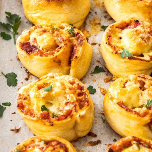 Close up of 8 pizza scrolls on a baking tray.