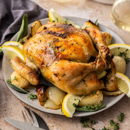 A golden roasted chicken in a serving platter.