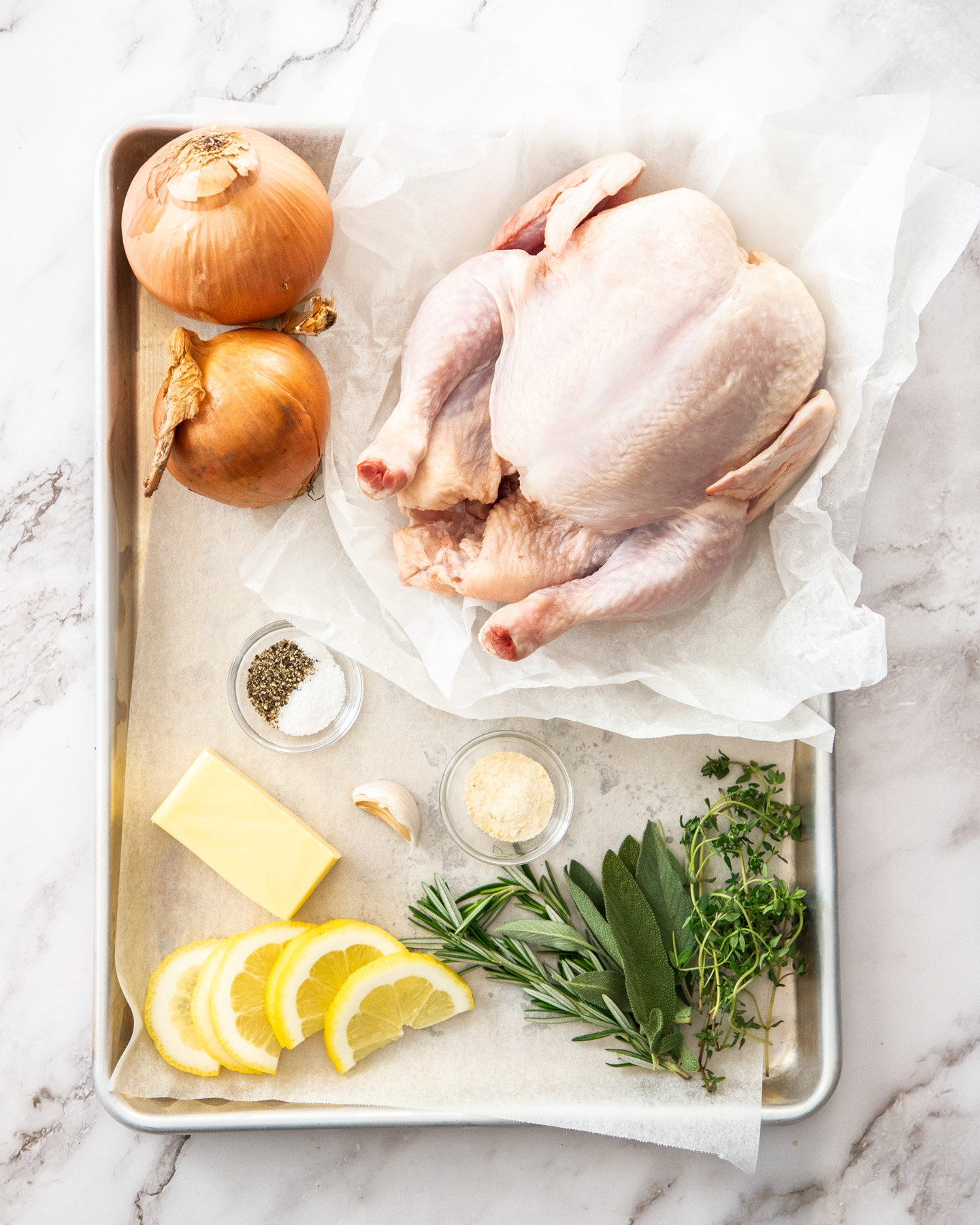 Ingredients for herb roasted chicken on a baking tray.