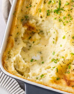 Mashed potato in a casserole dish with a scoop taken out.