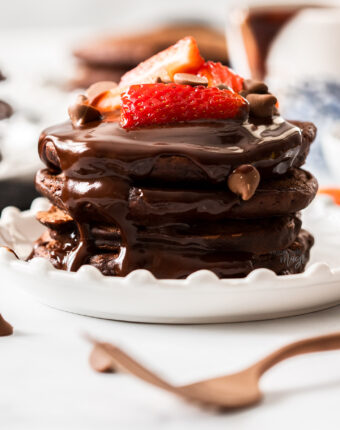 A stack of chocolate pancakes topped with strawberries.