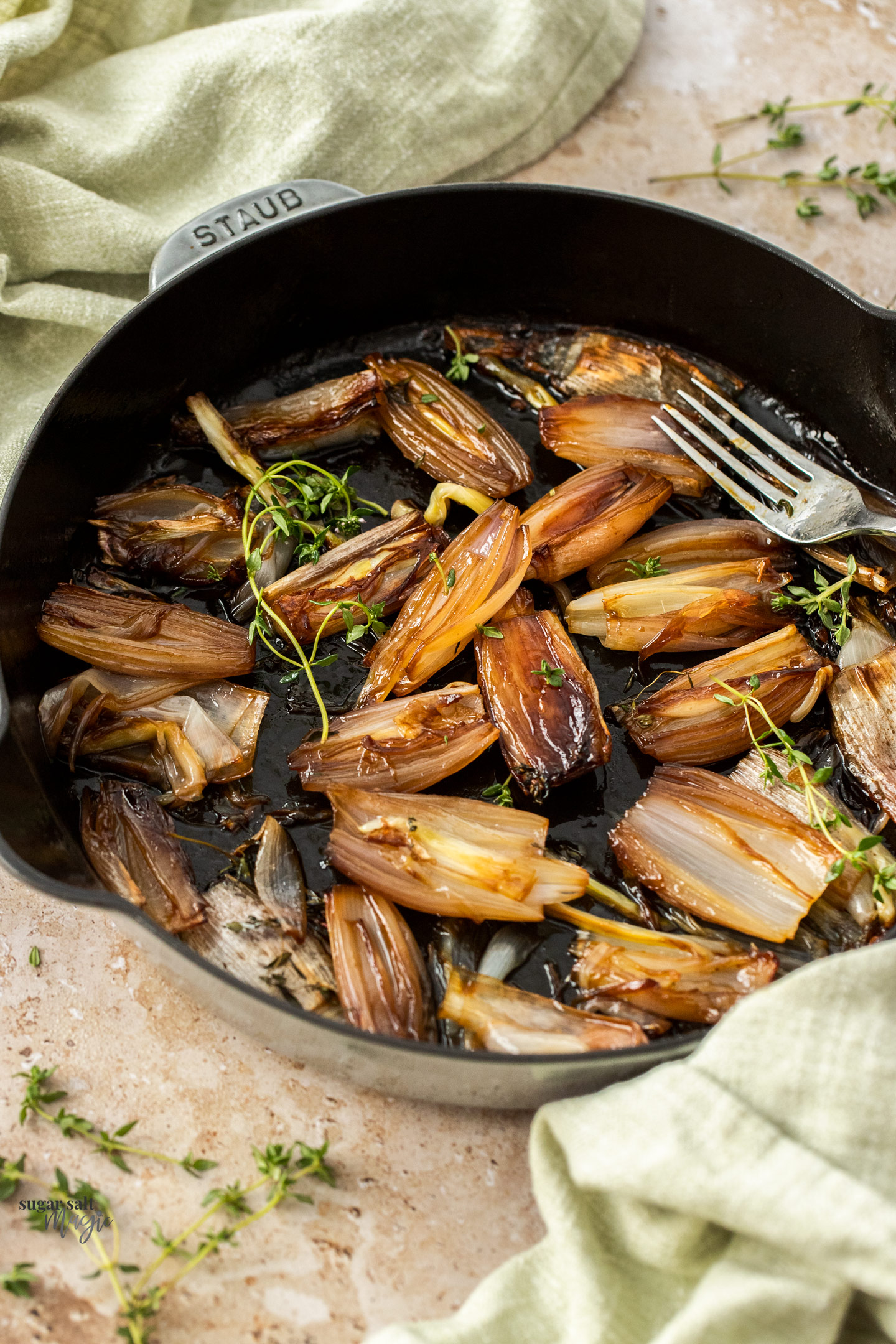 Roasted shallots in a pan with sprigs of thyme.