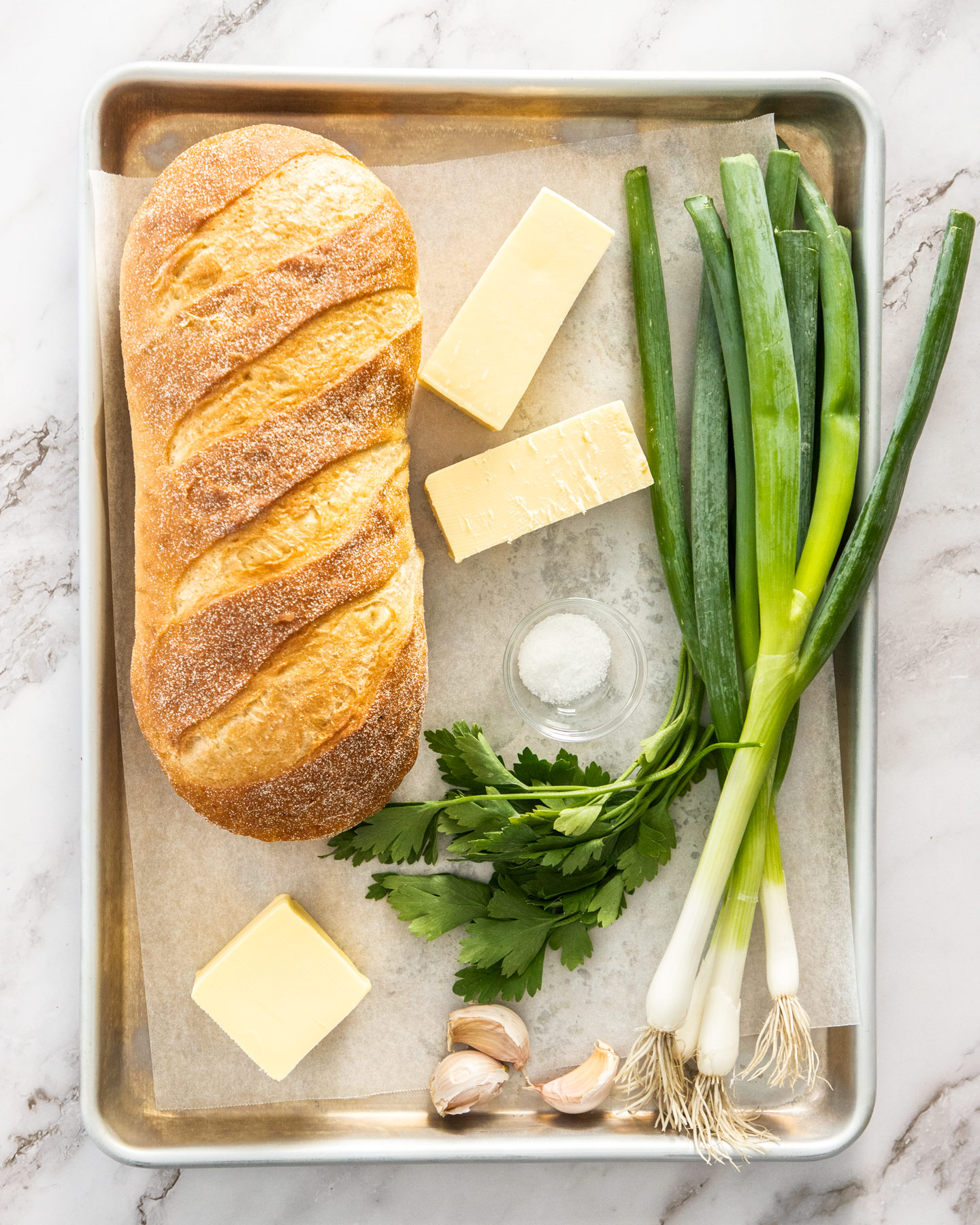 Ingredients for cheese and garlic crack bread on a baking tray.
