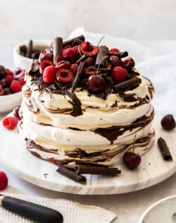 A 3 layered chocolate meringue cake topped with raspberries and cherries.