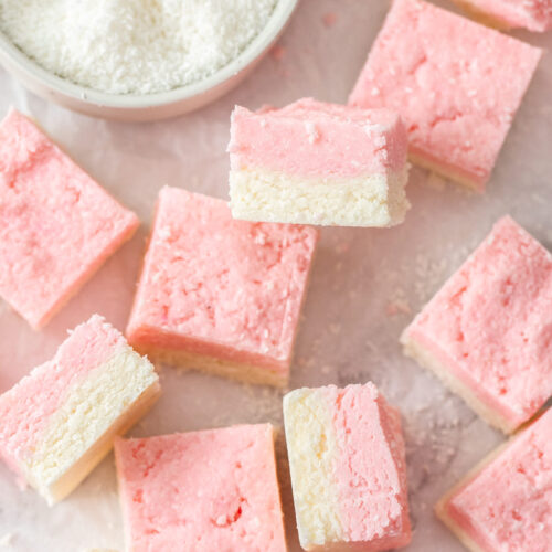 A batch of coconut ice squares on a marble benchtop.