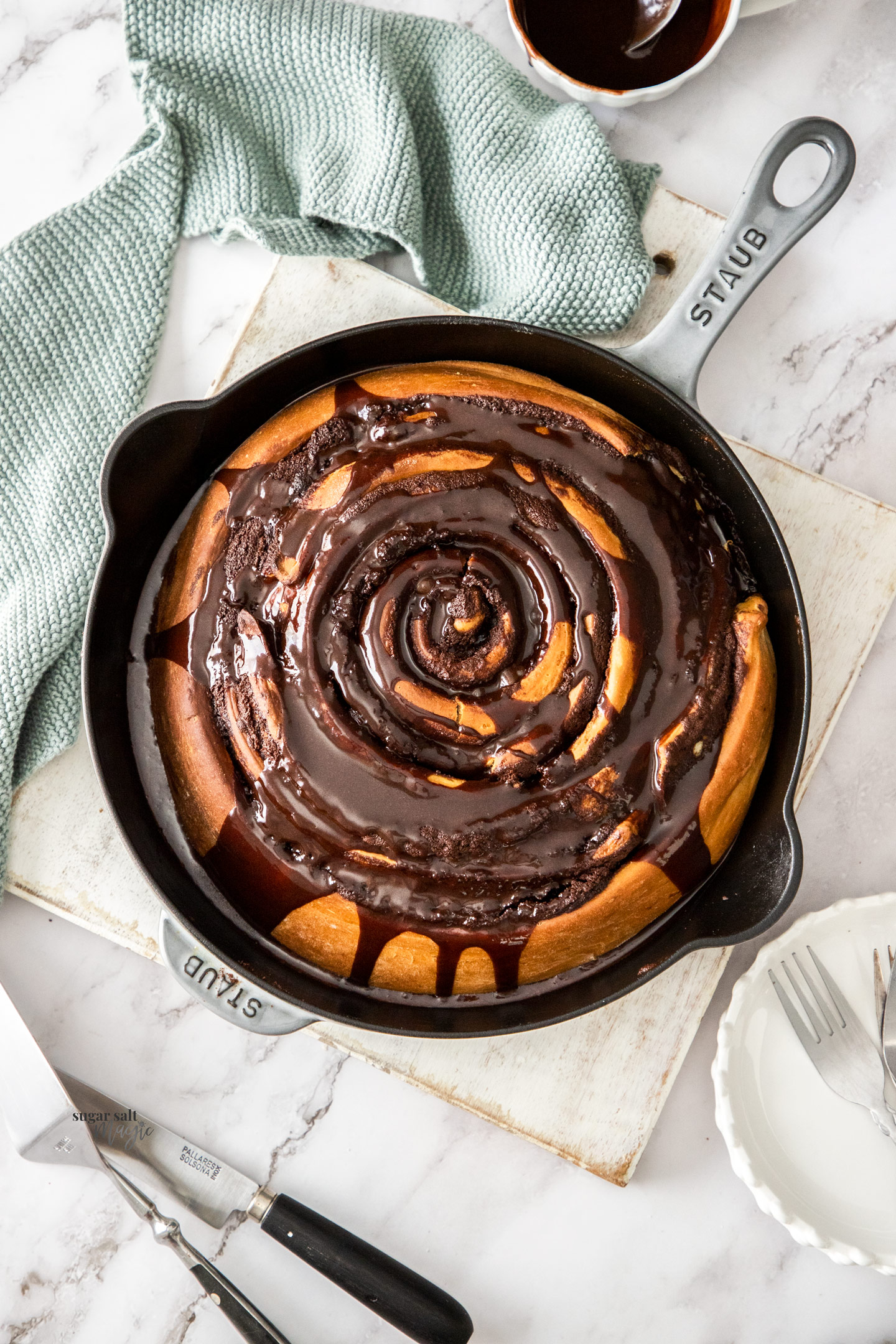 Top down view of a chocolate scroll coated in chocolate sauce.
