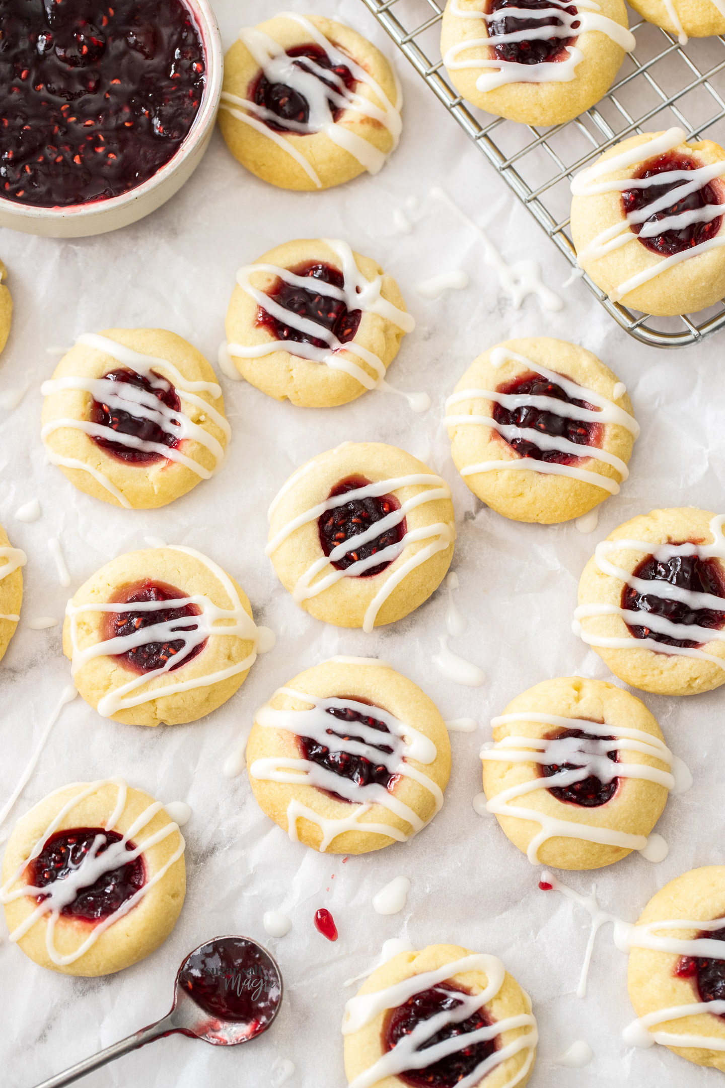 A batch of thumbprint cookies on a sheet of baking paper.