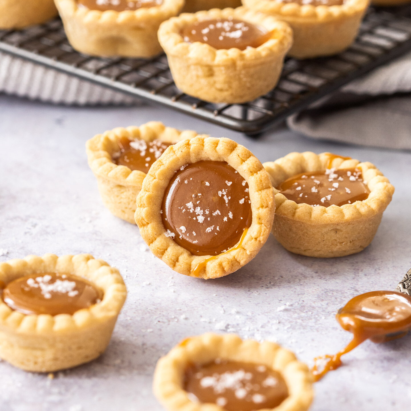 A batch of salted caramel tartlets with some on a wire rack.