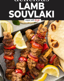 5 Greek lamb kebabs on a dark tray.