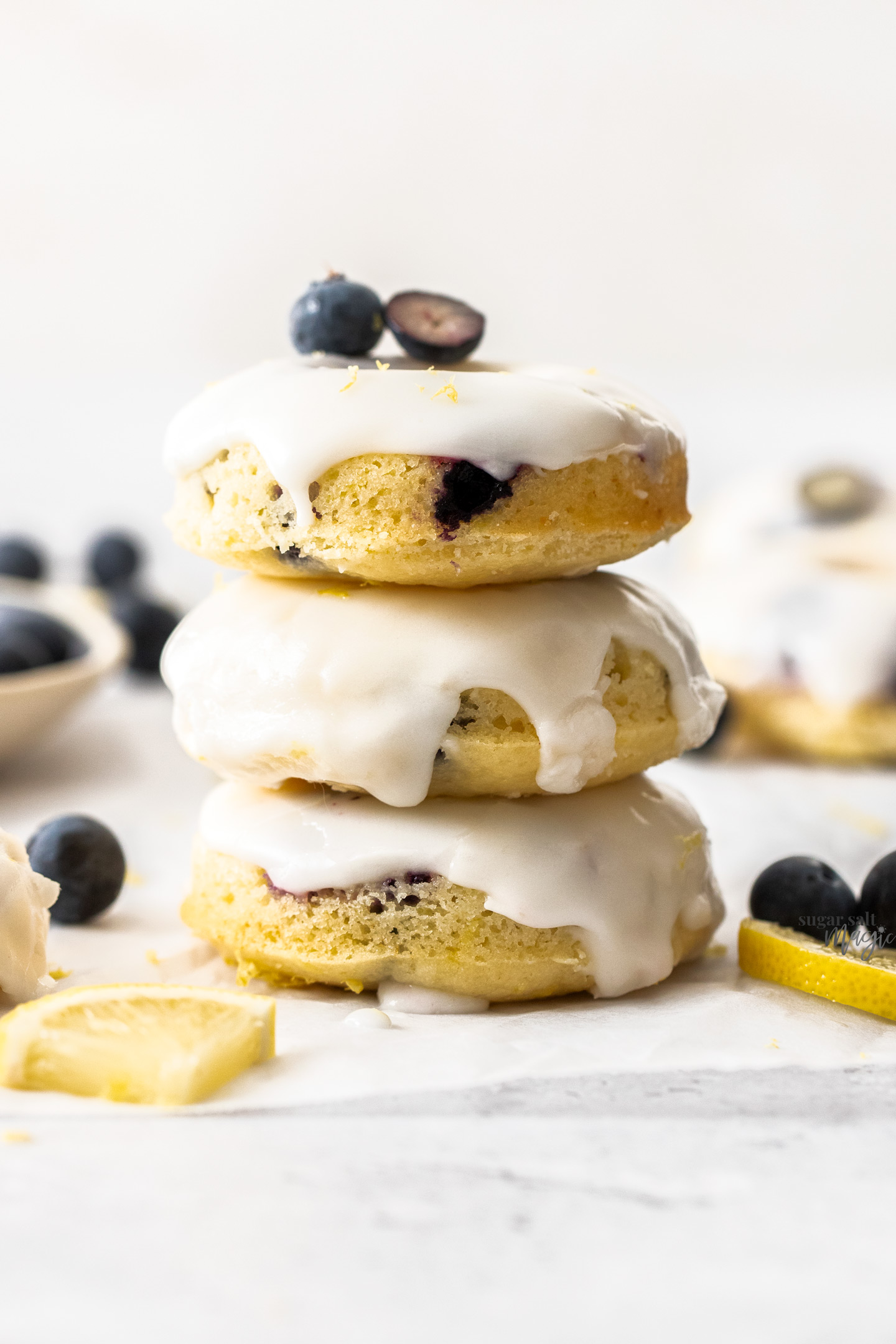 A stack of 3 iced blueberry donuts.