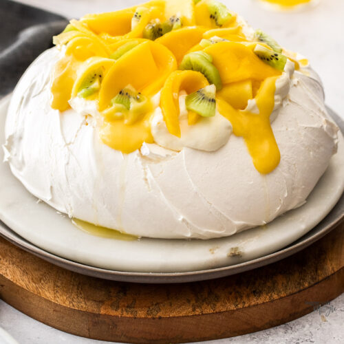 A whole pavlova topped with mango and cream.