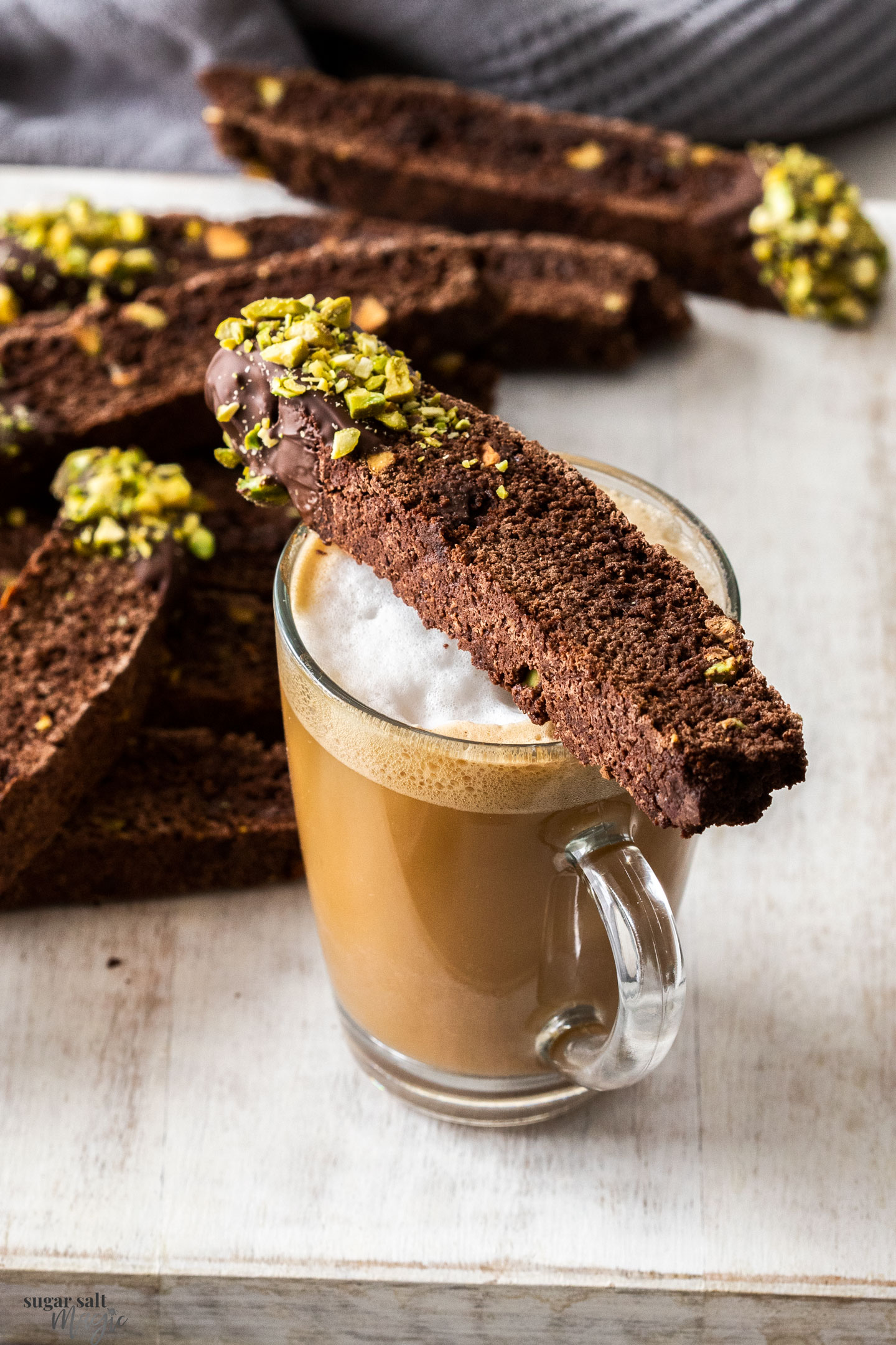 A chocolate biscotti sitting on a cup of coffee.