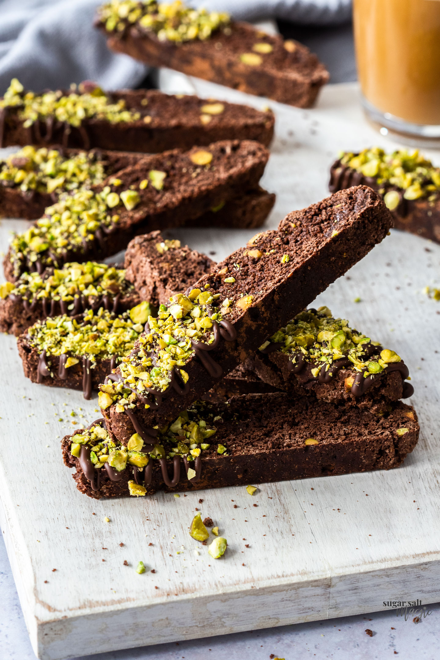 A pile of chocolate biscotti with pieces of pistachio.