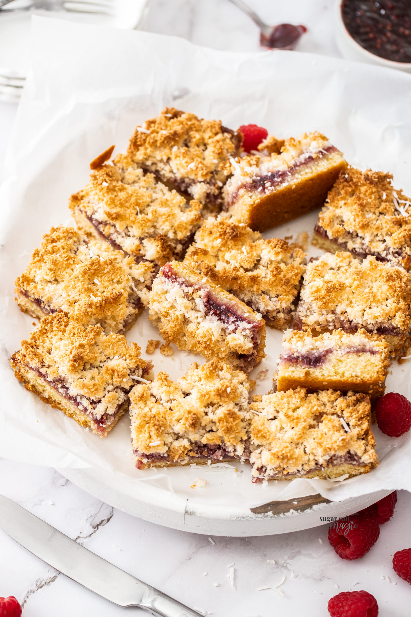 Pieces of raspberry coconut slice on a platter.