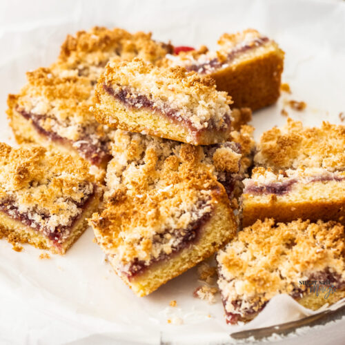A pile of raspberry coconut slice on a platter.