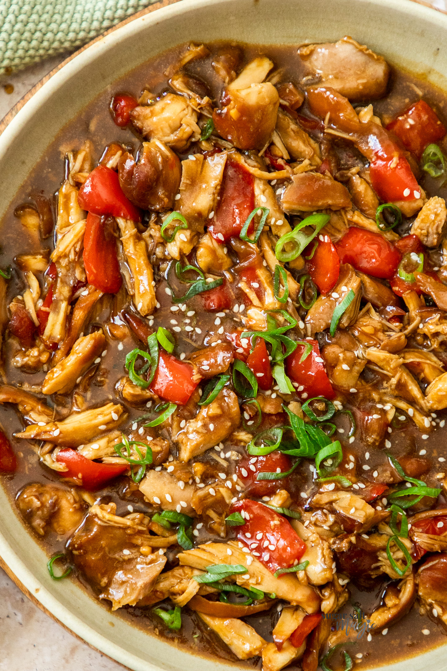 Top down view of shredded honey soy chicken in a large serving dish.