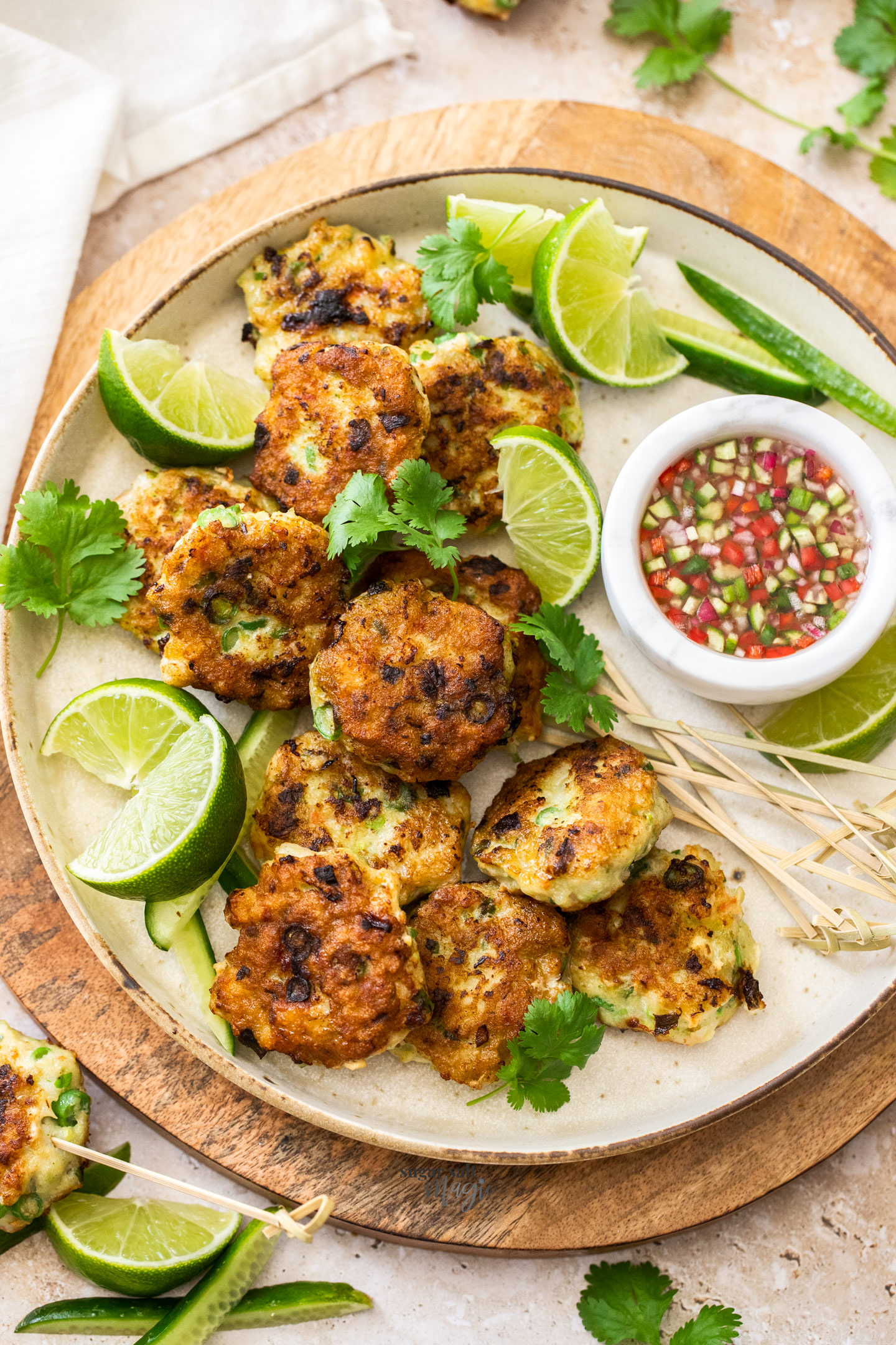 A batch of Thai fish cakes on a platter with sauce.