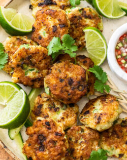 Close up of Thai fish cakes with lime wedges.