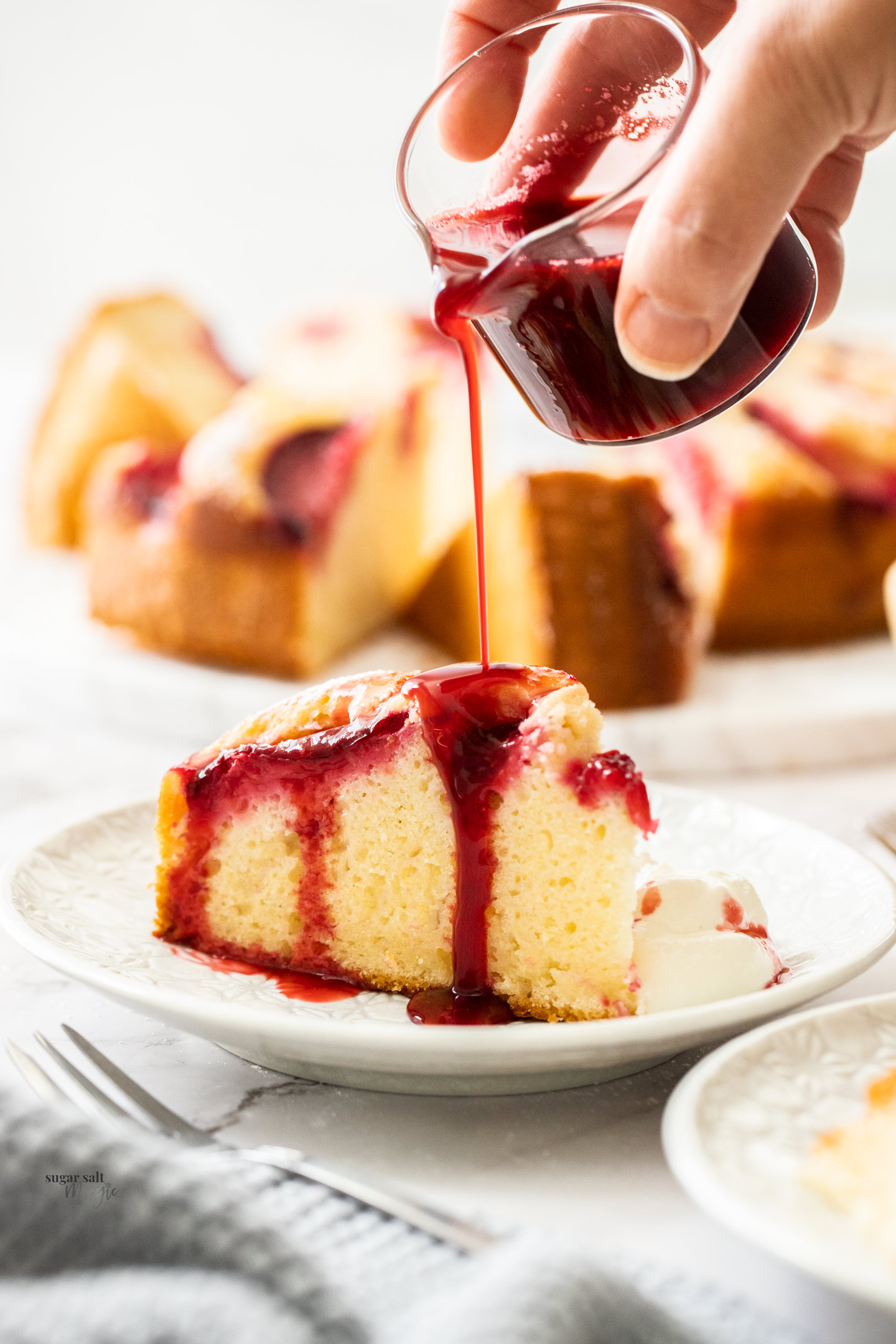 Syrup being poured over a slice of cake.