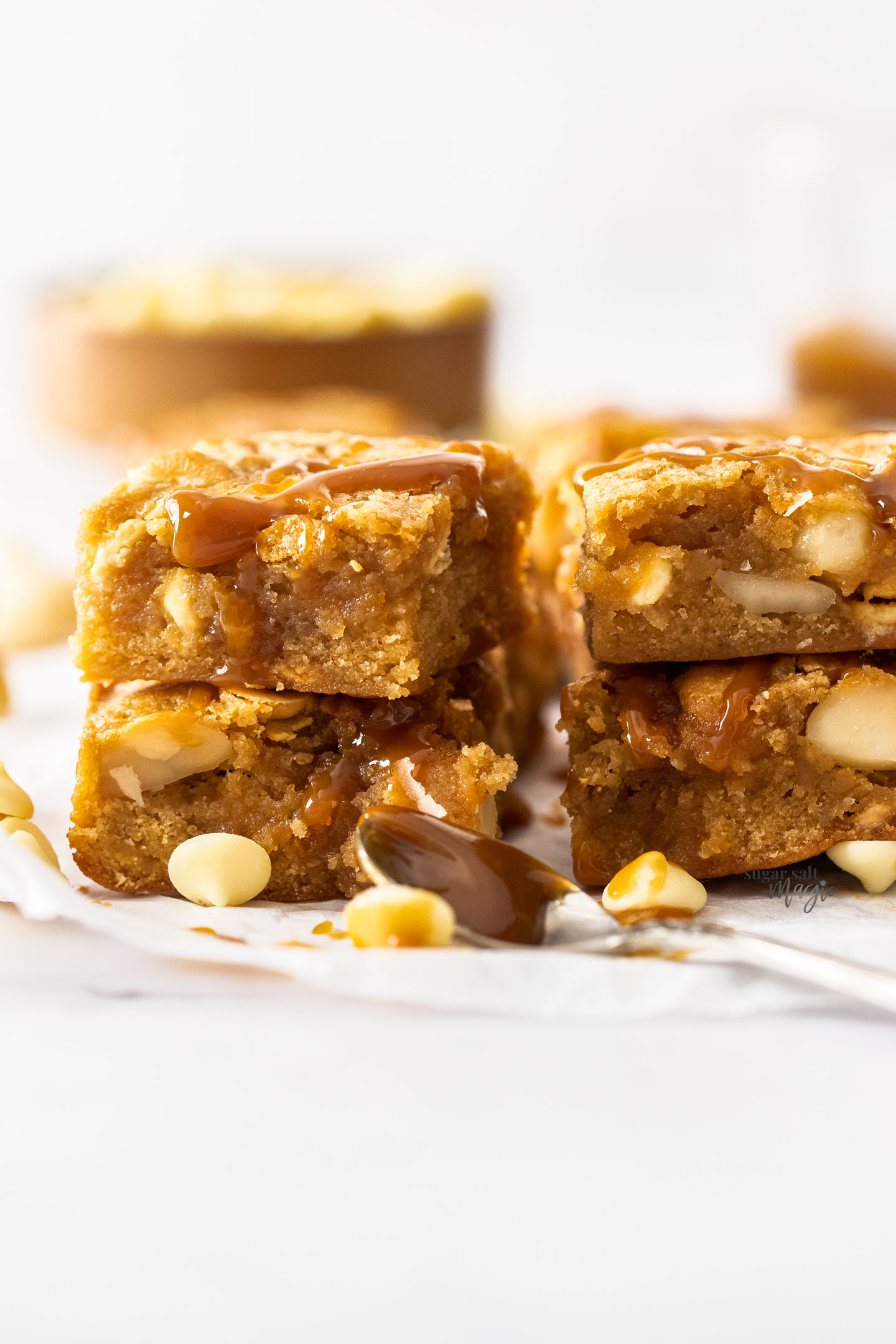 Stacks of 2 blondies with white chocolate chips next to them.