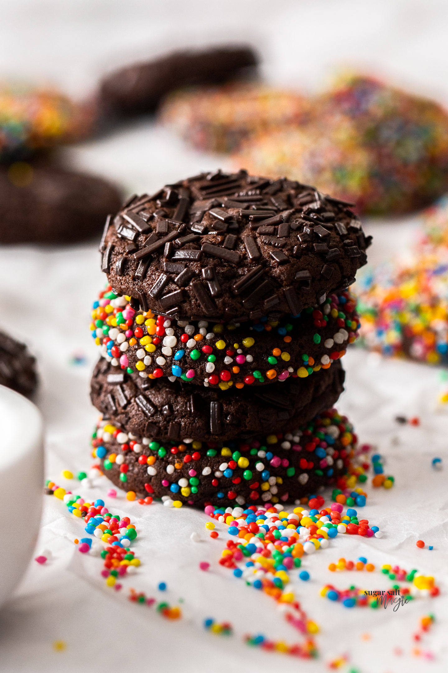 A stack of 4 chocolate sprinkle cookies.