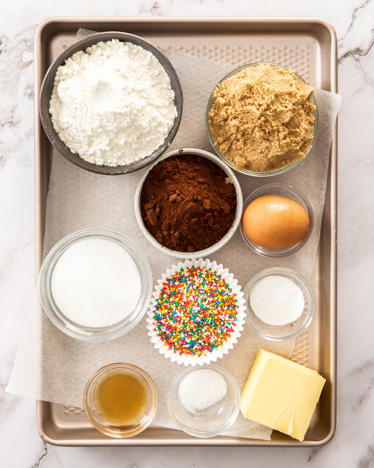 Ingredients for chocolate sprinkle cookies on a baking tray.
