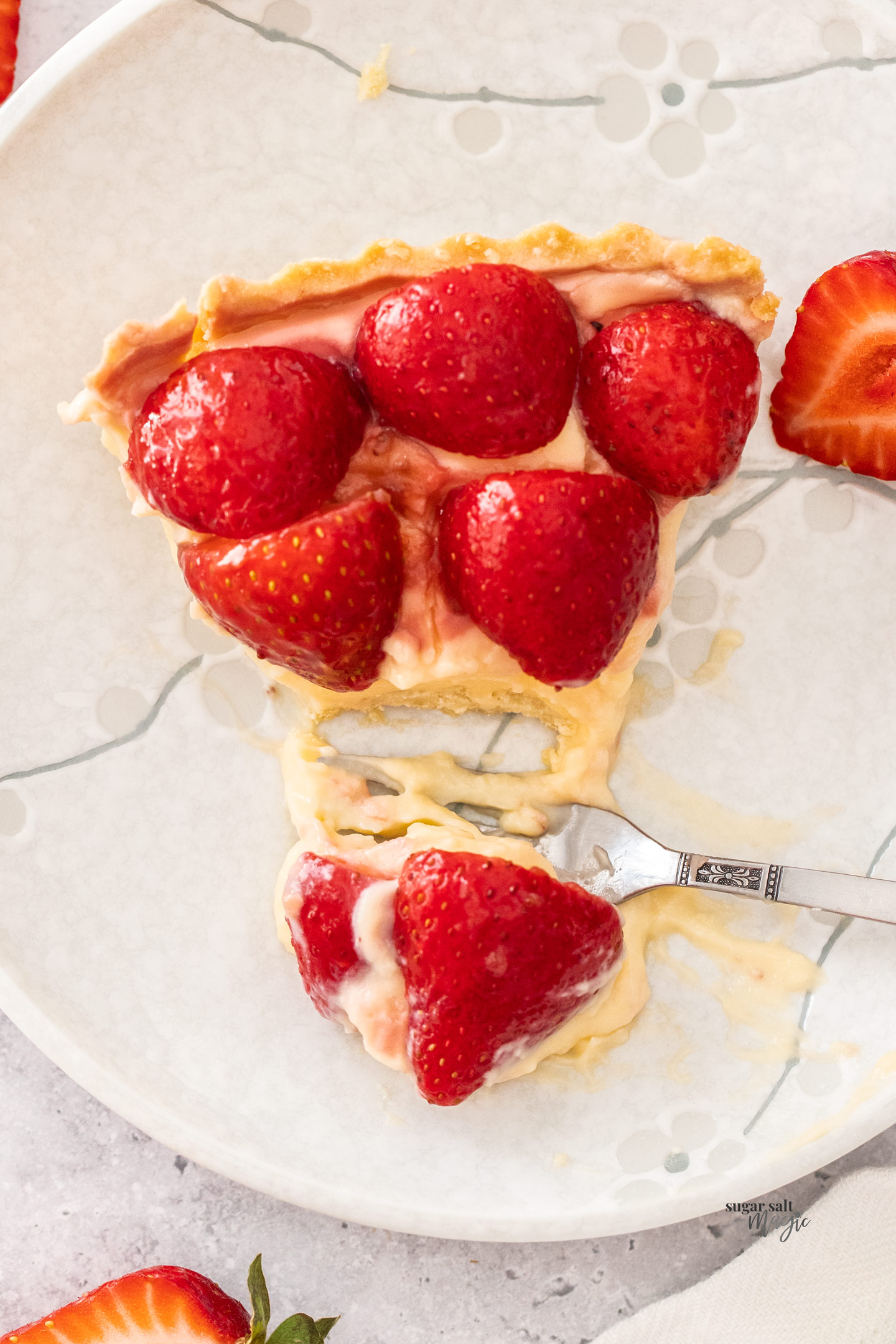Top down view of a slice of strawberry tart with some cut away.