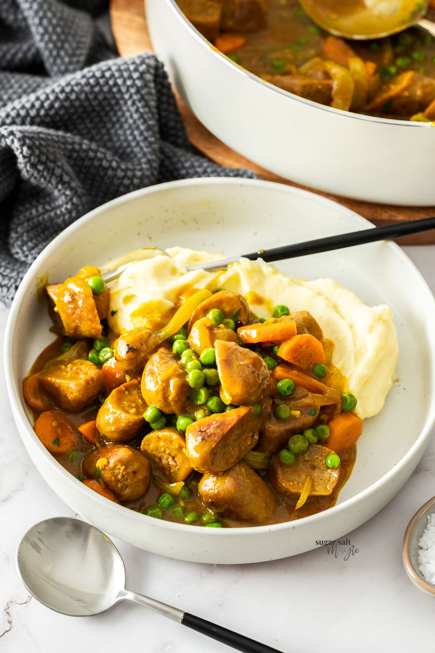 Curried sausages over mashed potato in a bowl.
