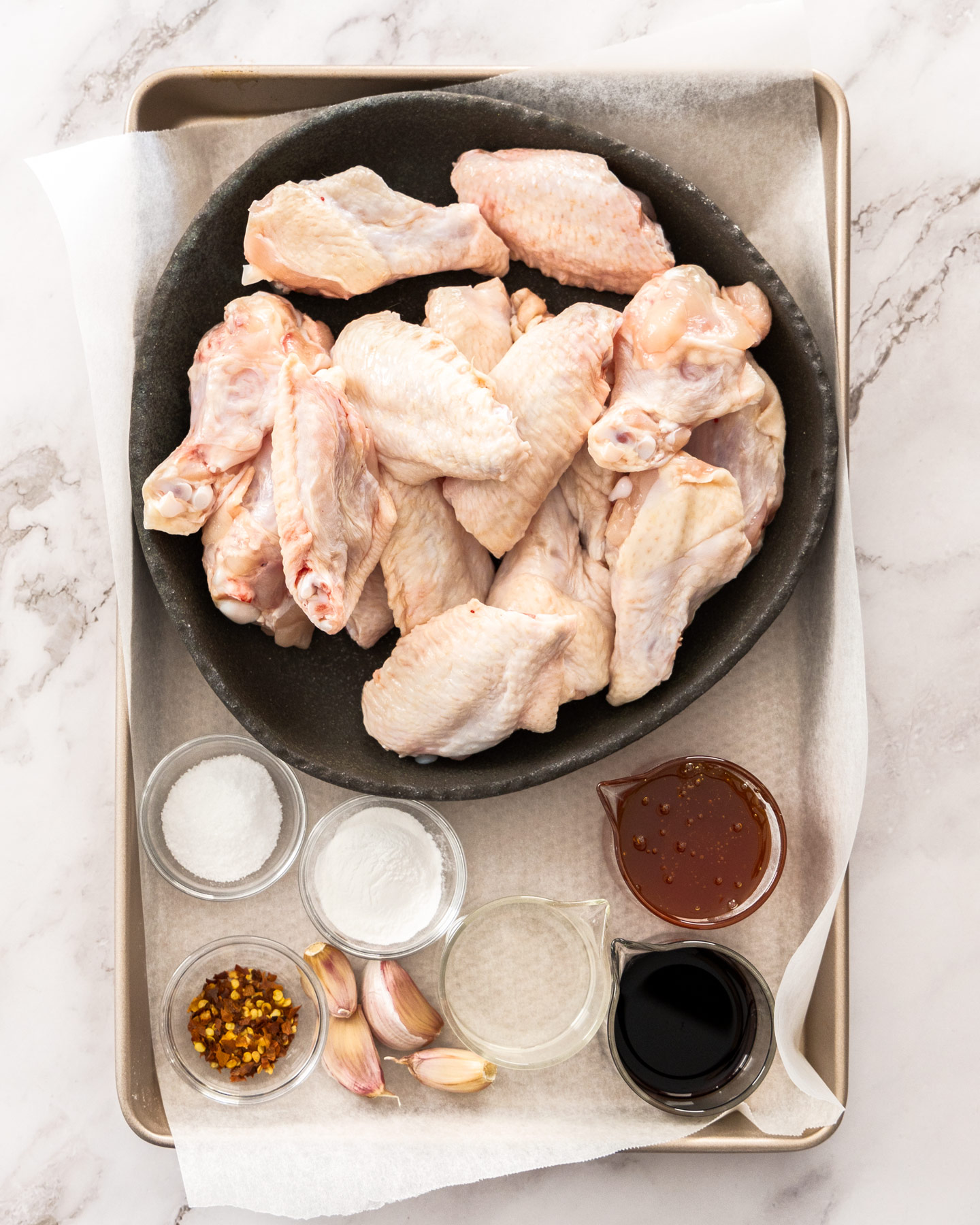 Ingredients for honey garlic chicken wings on a baking tray.