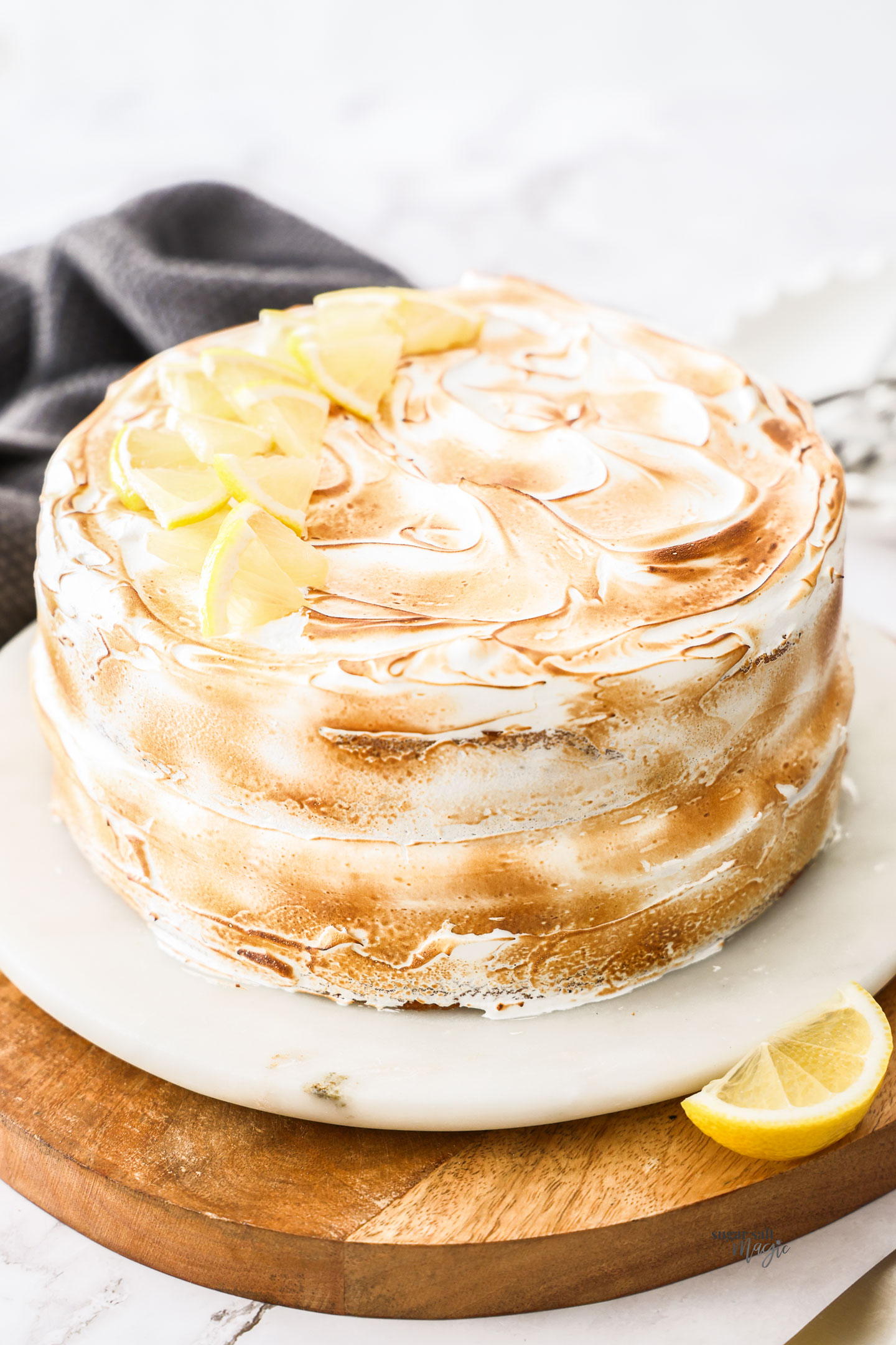 A whole lemon meringue cake on a cake platter.