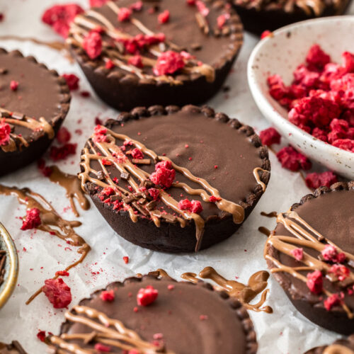 Closeup of a chocolate tartlet drizzled with chocolate and raspberries.