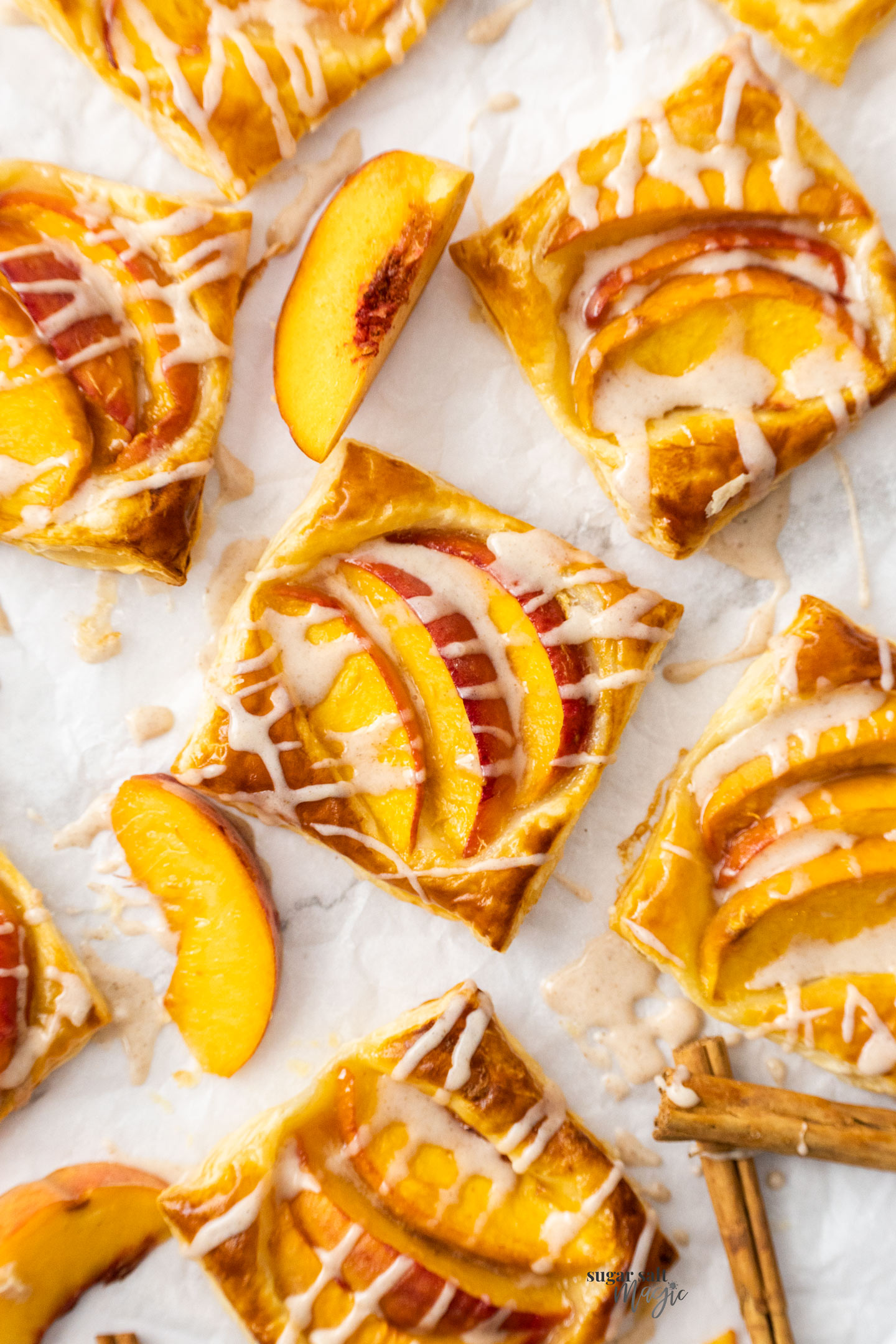 Mini puff pastry peach tarts on a sheet of baking paper.
