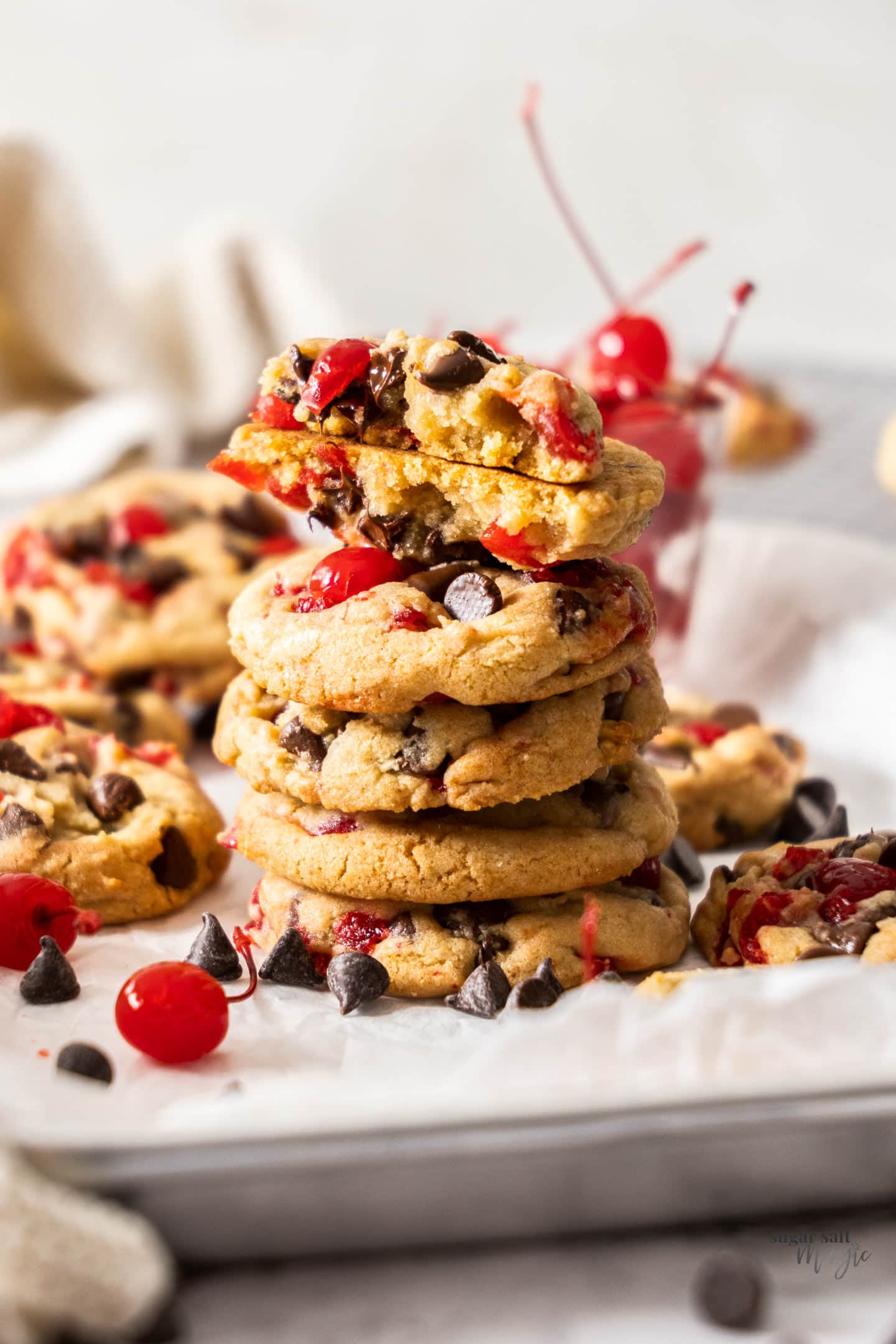 A stack of cherry chocolate chip cookies with the top one broken in half to show inside.