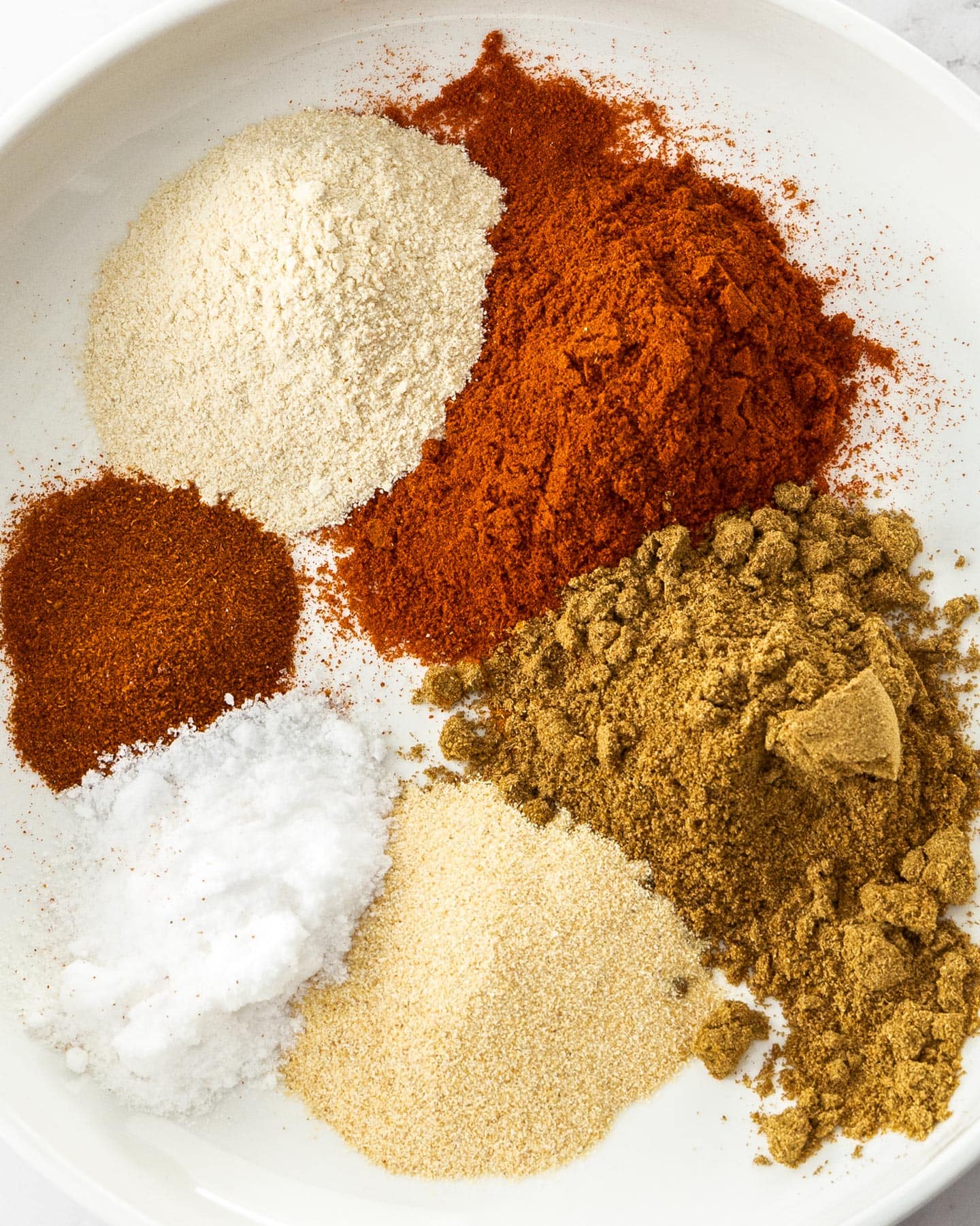 Different spices in piles on a plate.