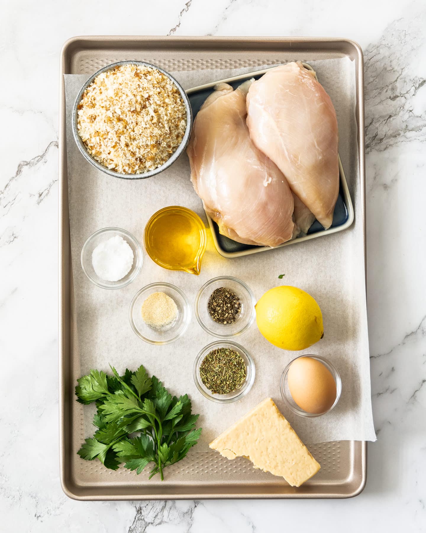 Ingredients for Italian chicken cutlets on a baking tray.