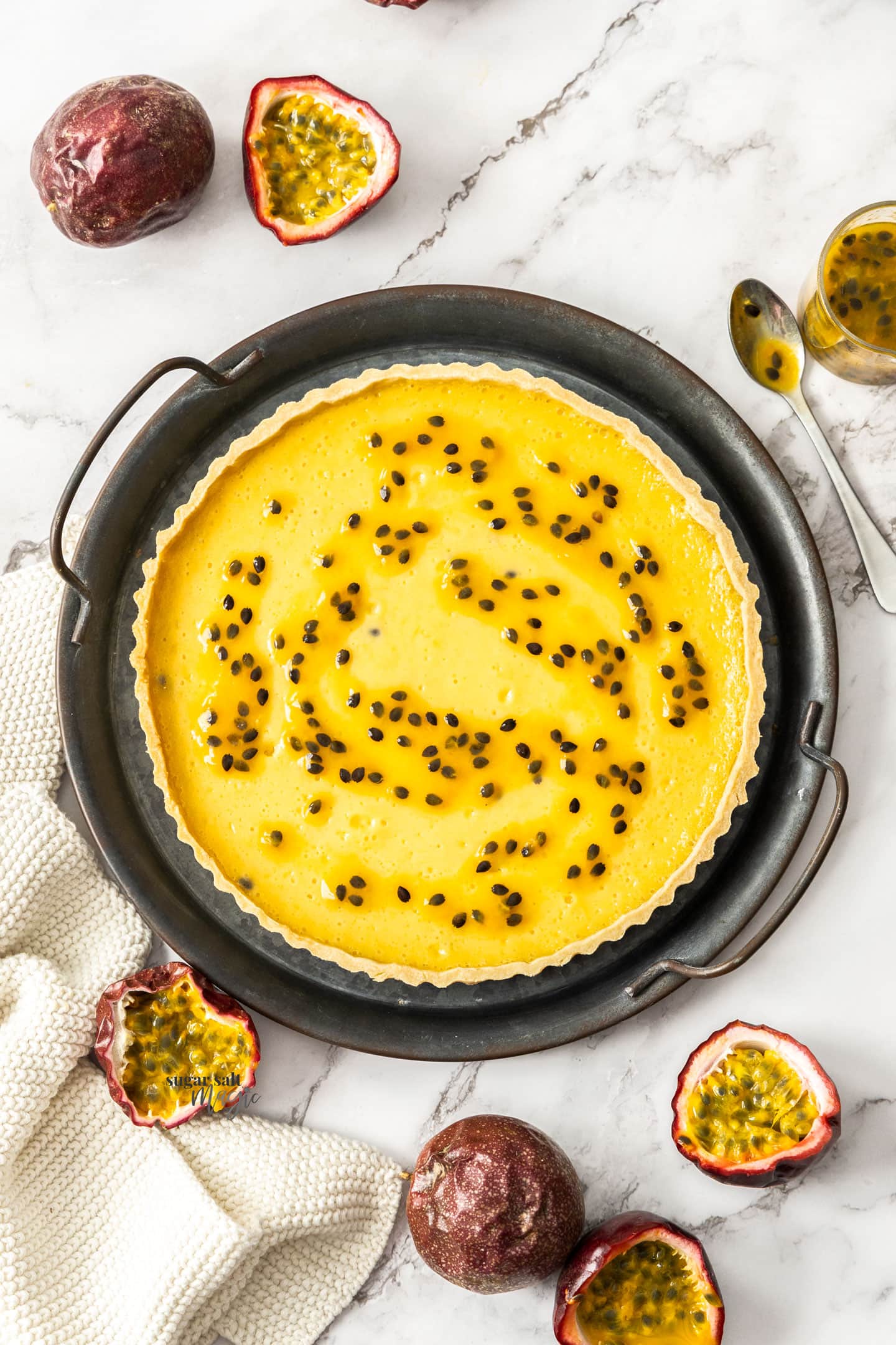 Top down view of a passionfruit filled tart on a metal tray.