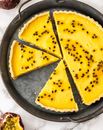 A passionfruit tart cut into slices on a metal tray.